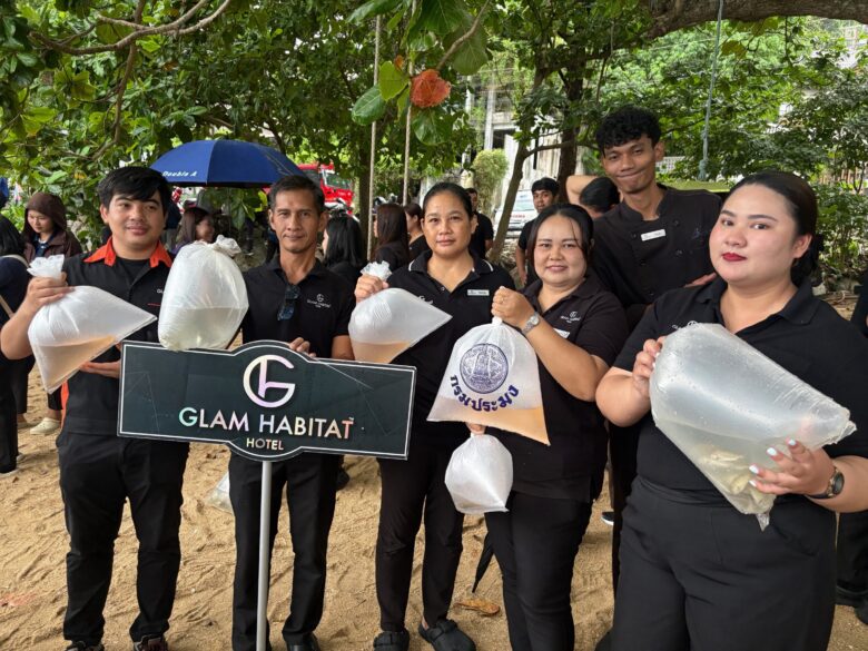 Glam Habitat team members holding bags of fish fry beside the hotel sign at Kamala's 2026 aquatic life release event