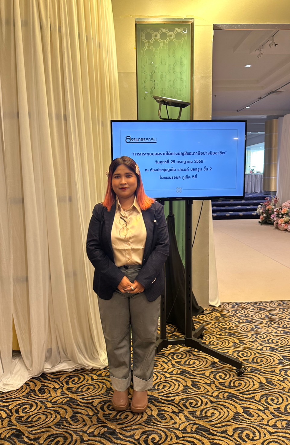 Glam Habitat staff member standing beside the event signage for the accounting and tax revenue reconciliation seminar