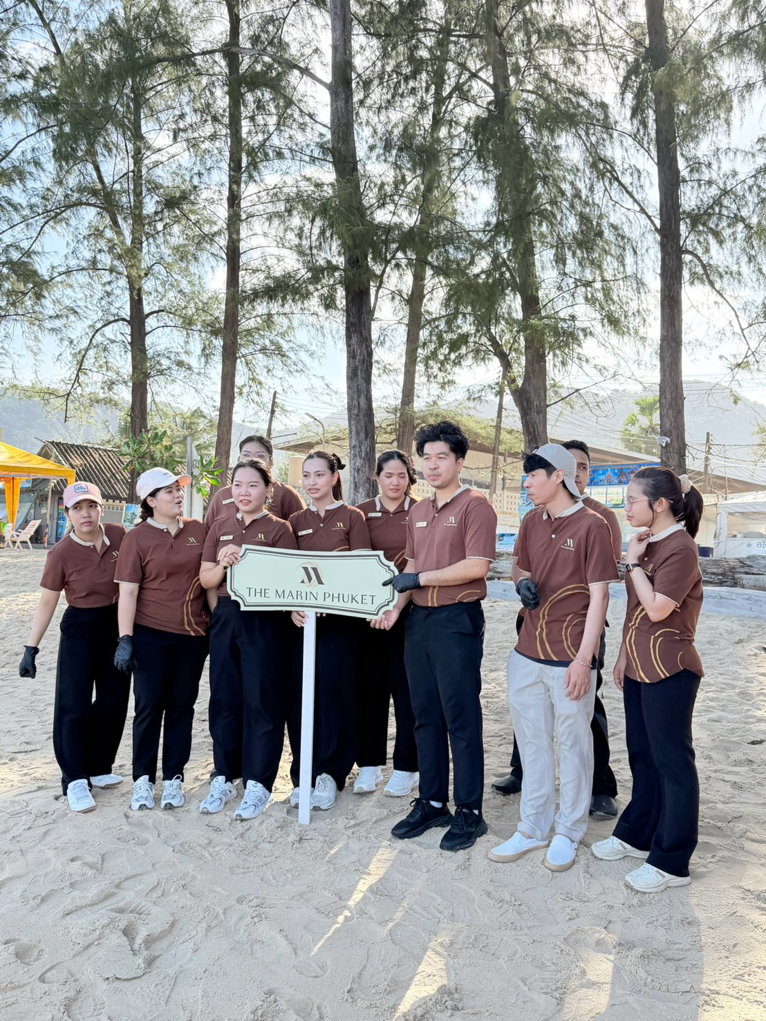 The Marin Phuket team holding their hotel sign at the Kamala Beach cleanup