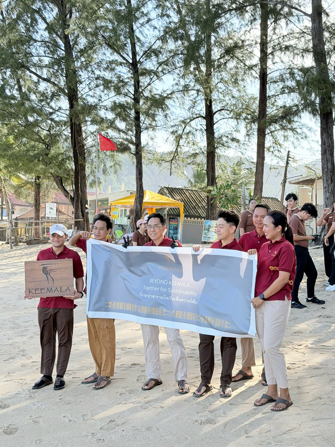 Keemala team holding the Beyond Keemala: Together for Sustainability banner on Kamala Beach