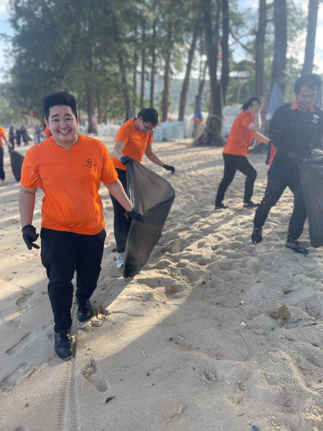 A Glam Habitat team member carrying a full rubbish bag along Kamala Beach