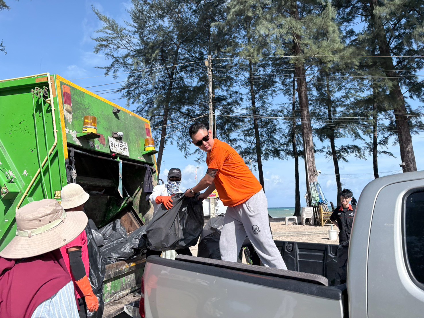 Volunteers loading bagged waste onto a municipal garbage truck