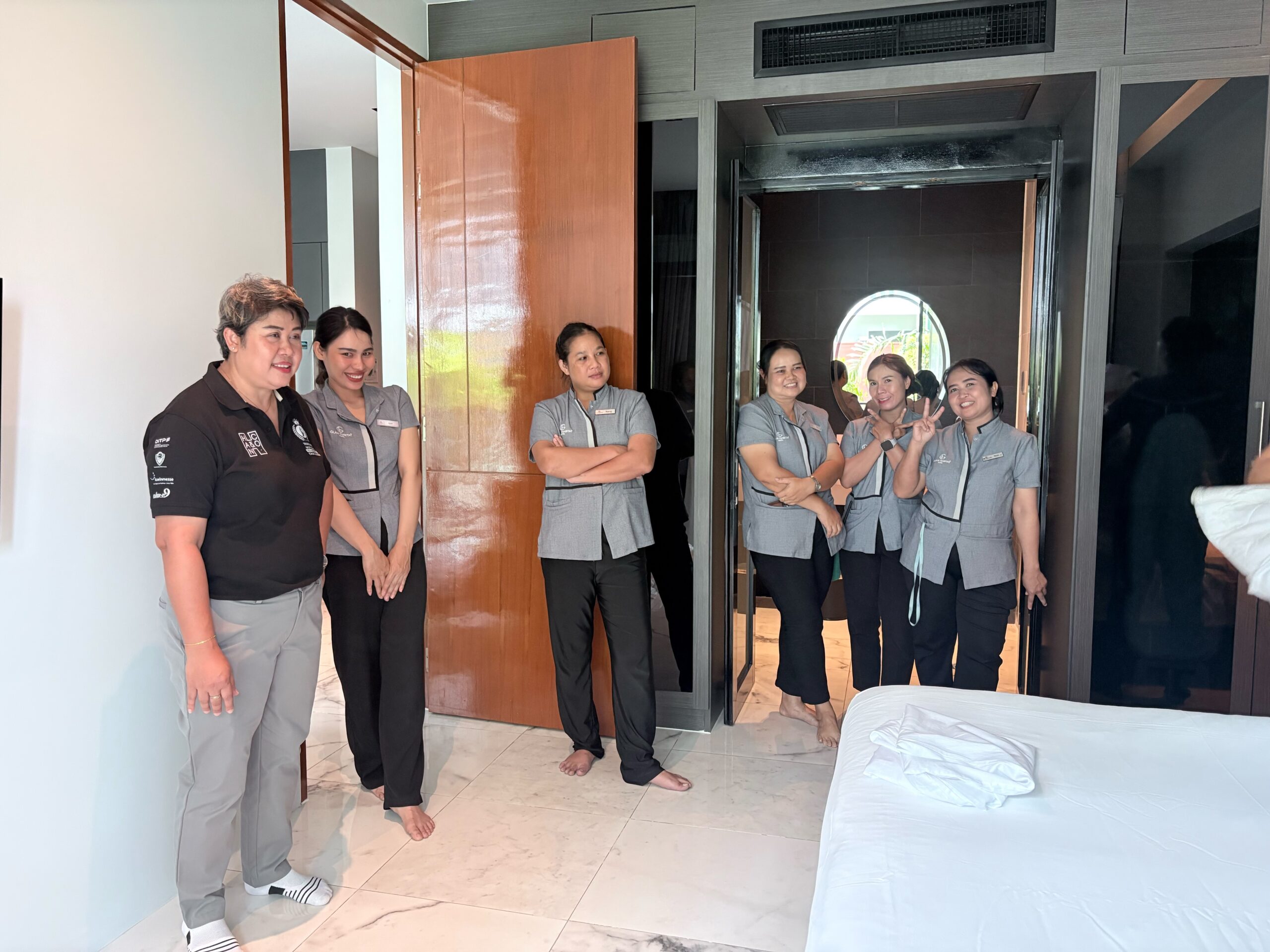 Glam Habitat housekeeping team gathered in a guest suite doorway during a training session