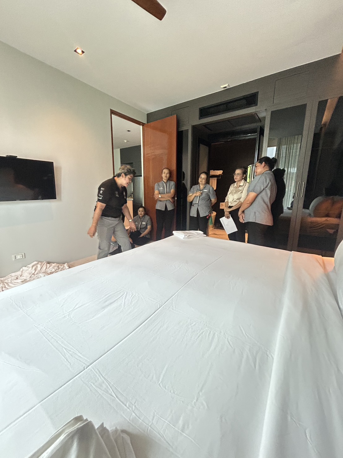 Housekeeping team practicing bed presentation with towels and pillows in a guest suite