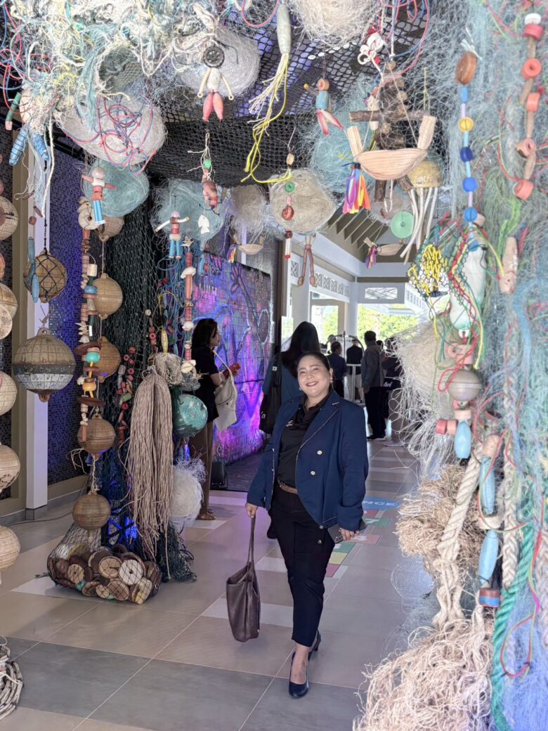 A Glam Habitat Hotel team member walking through a recycled fishing-net art installation at the PHIST 2026 sustainable tourism event