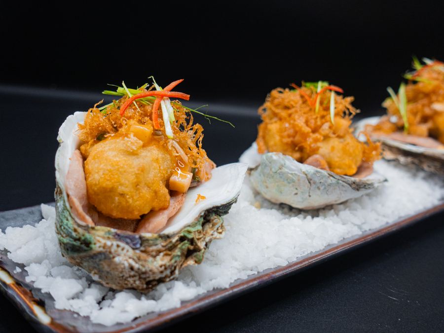 Oysters on the half shell with crisp toppings, served on a bed of salt