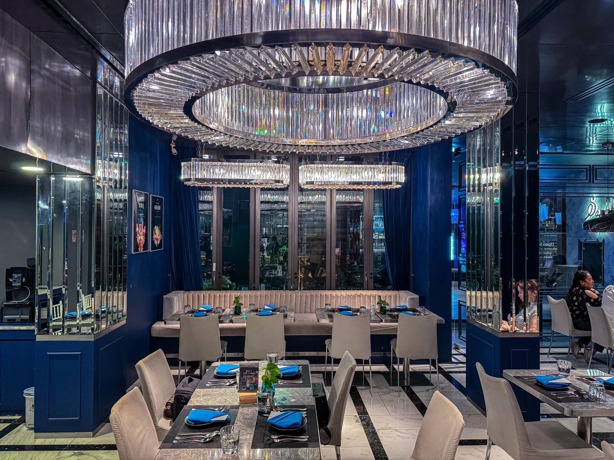 Sapphire Creative Cuisine dining room at Glam Habitat Hotel, with a crystal chandelier above deep sapphire-blue walls and set tables