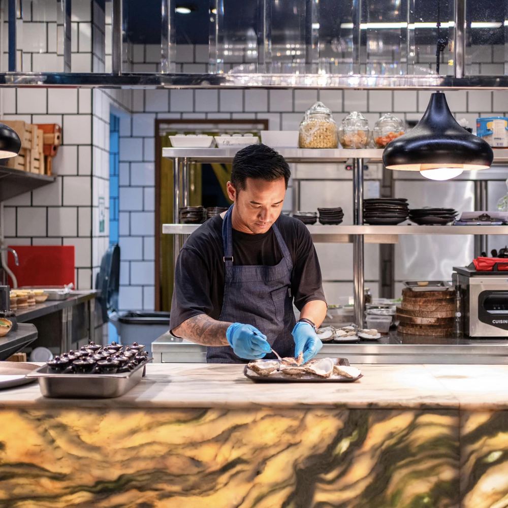 A cook preparing a dish at the counter of Sapphire's open kitchen
