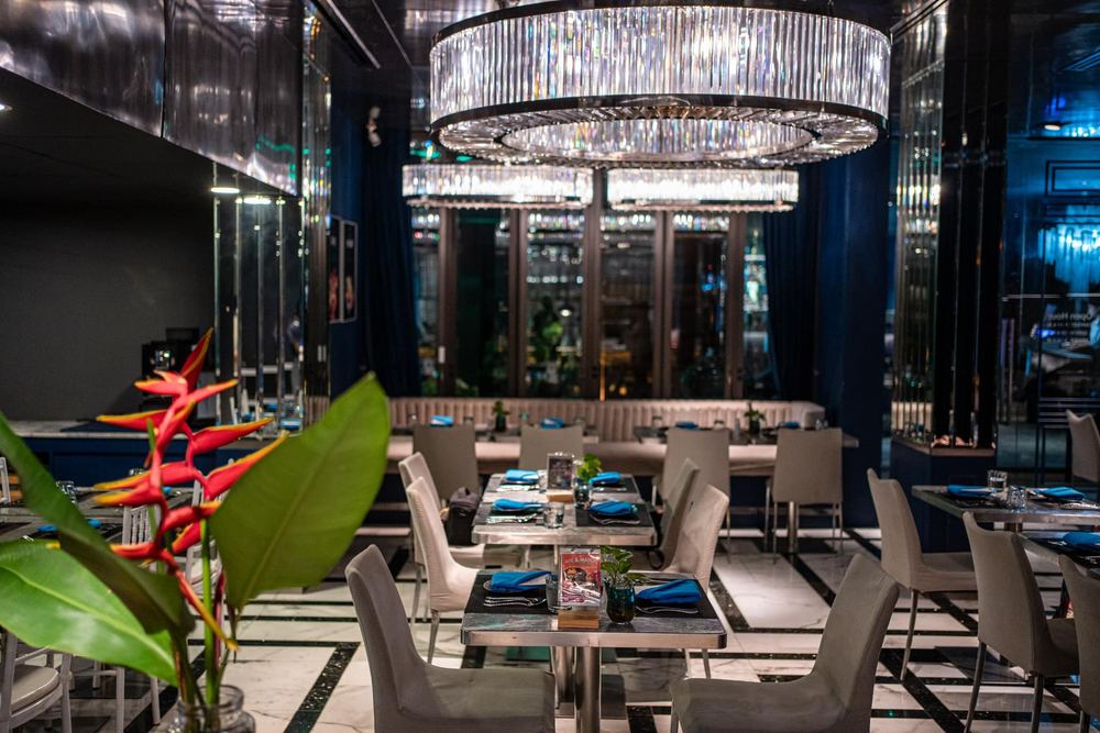 Sapphire dining room with crystal chandeliers, blue walls and tropical heliconia flowers