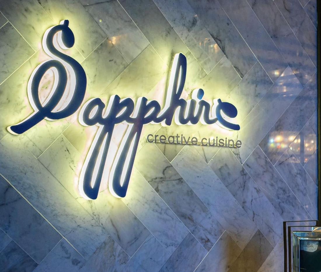Illuminated Sapphire creative cuisine sign on a marble wall at the restaurant entrance