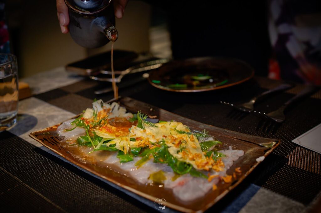 Sauce being poured over a plated dish at a Sapphire table