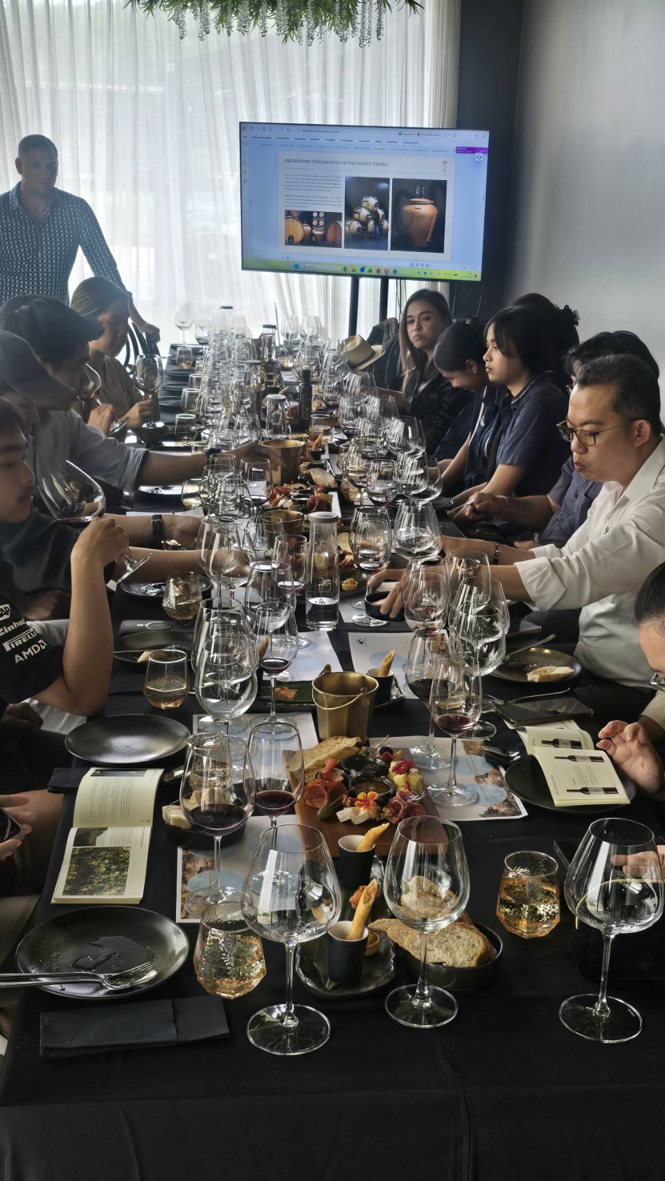 Masterclass guests tasting red wine and reading the Villa Saletta booklet around a long table