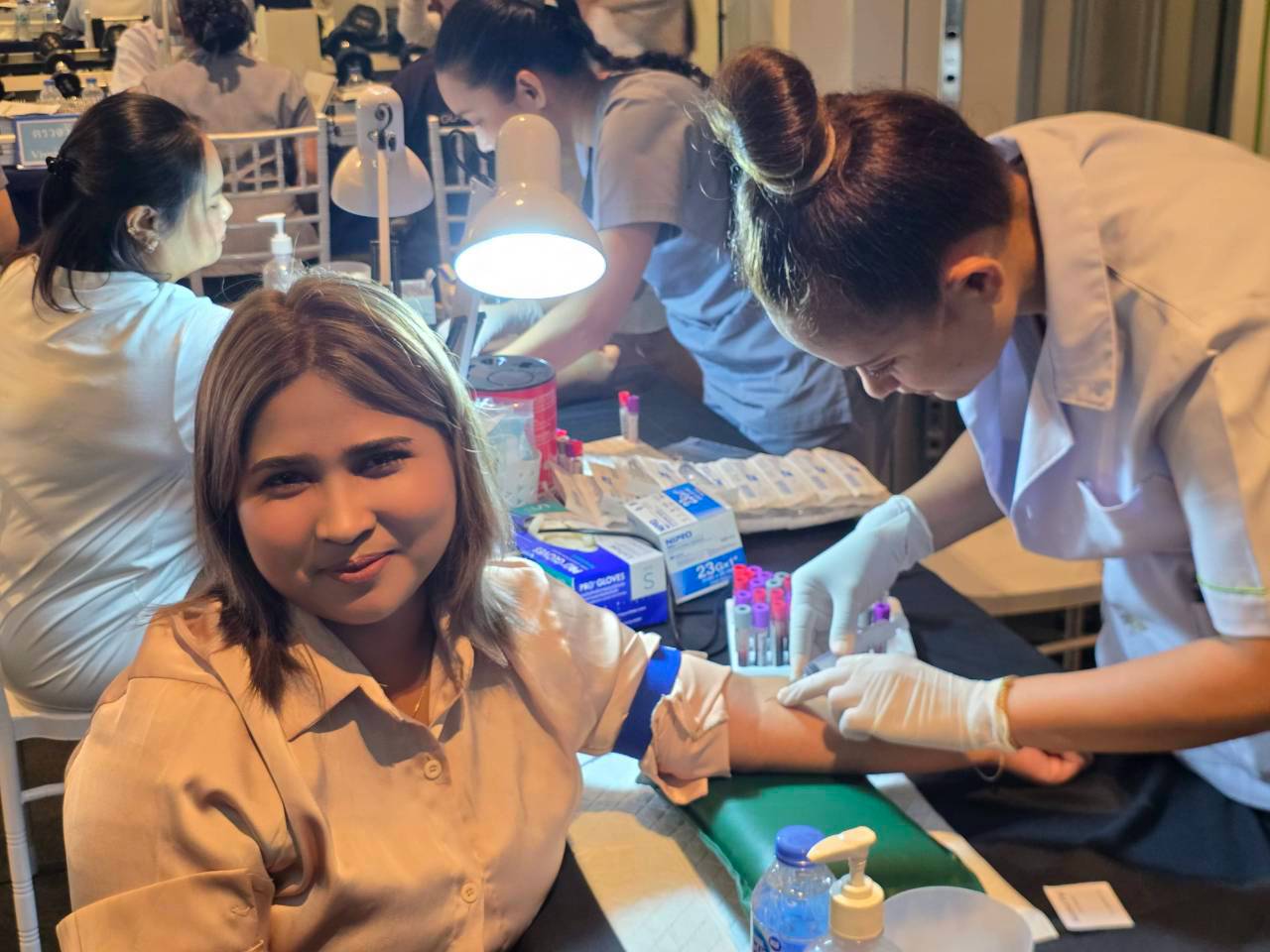 A smiling Glam Habitat team member during blood collection at the on-site staff health check