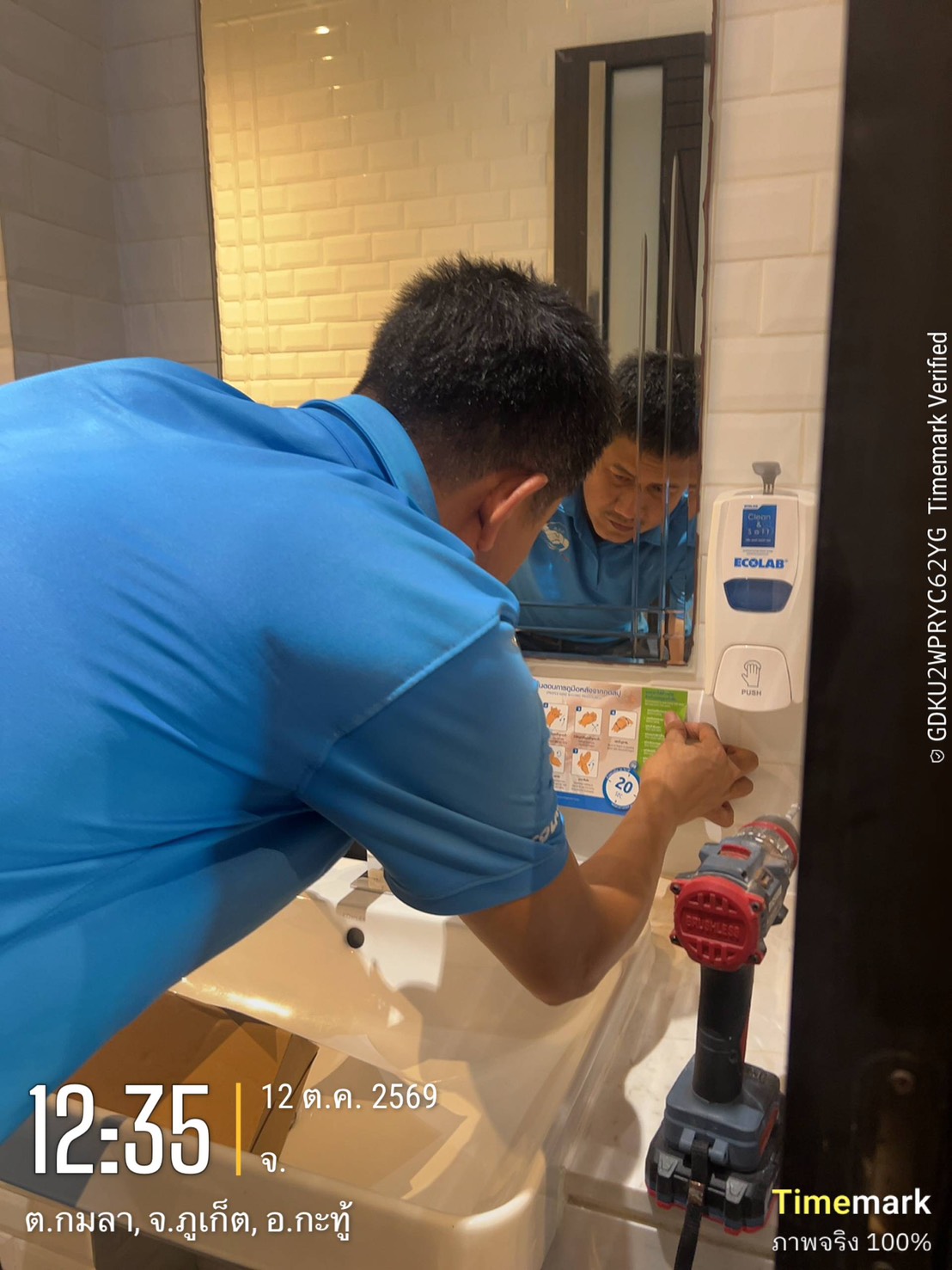 An ECOLAB technician placing a seven-step hand washing poster beneath a newly installed Clean & Soft soap dispenser